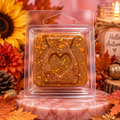 Golden Autumn sample wax melt with a heart design and gold flecks in clear packaging among autumn decorations.