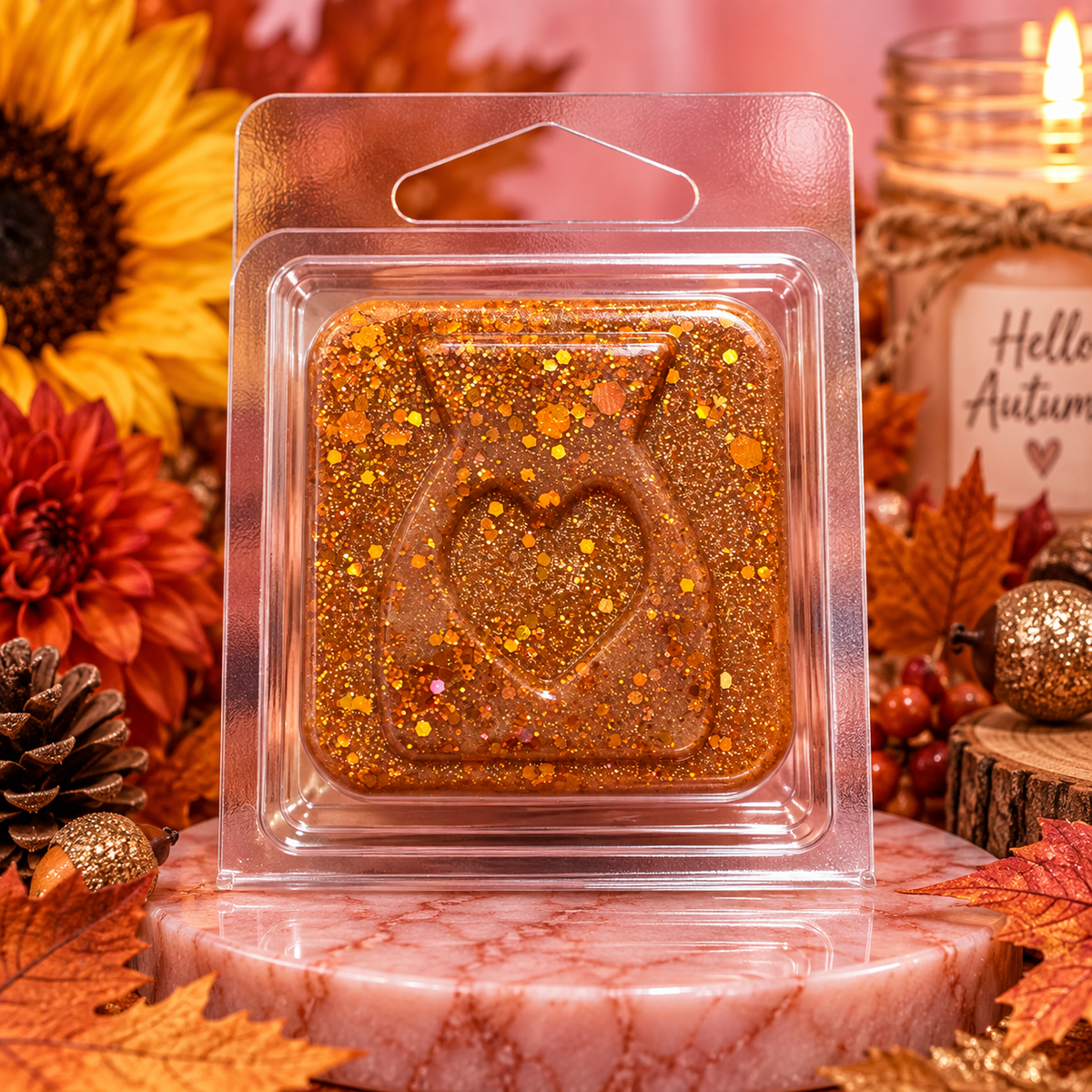 Golden Autumn sample wax melt with a heart design and gold flecks in clear packaging among autumn decorations.